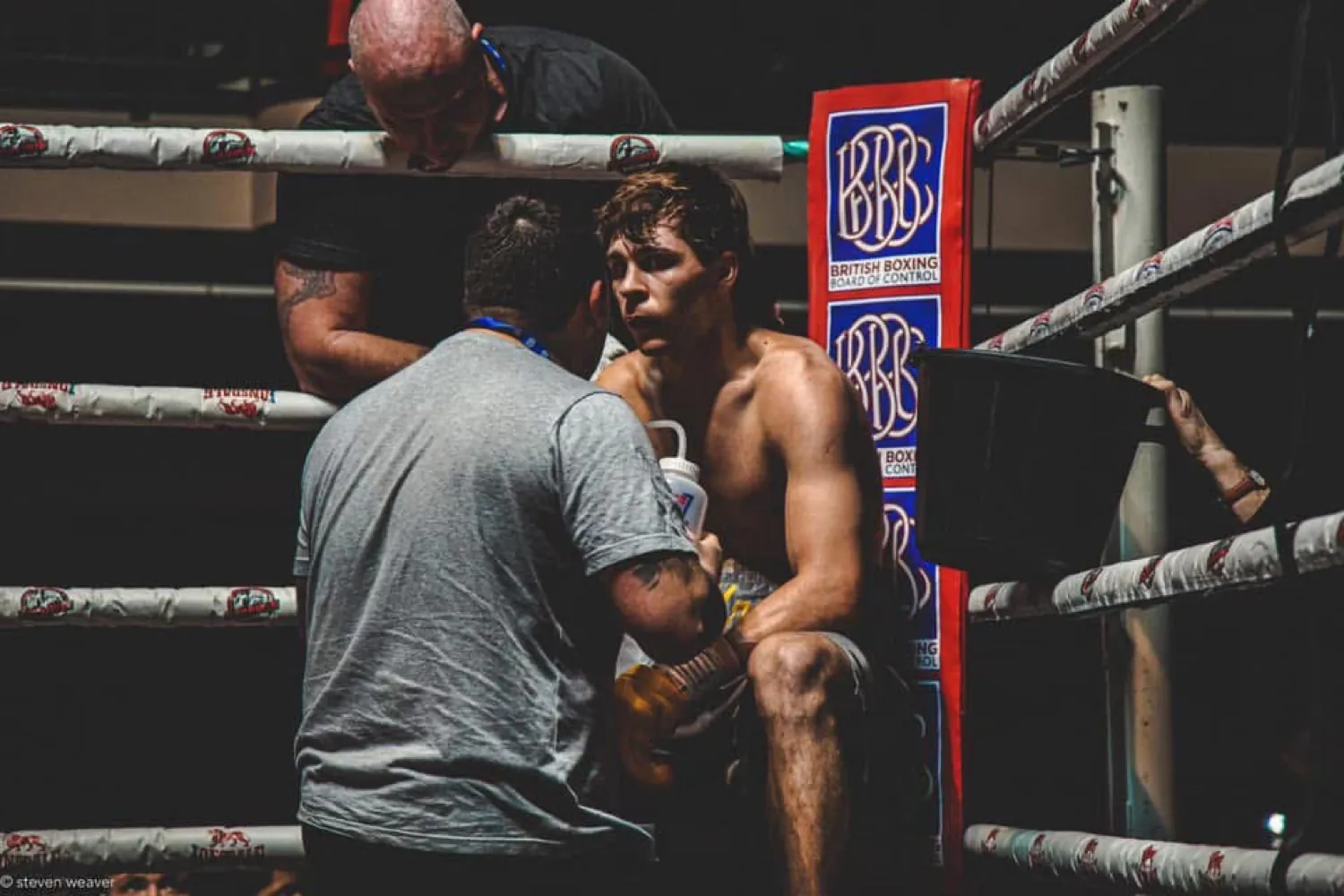 Coach giving instructions to a seated boxer in the corner between rounds