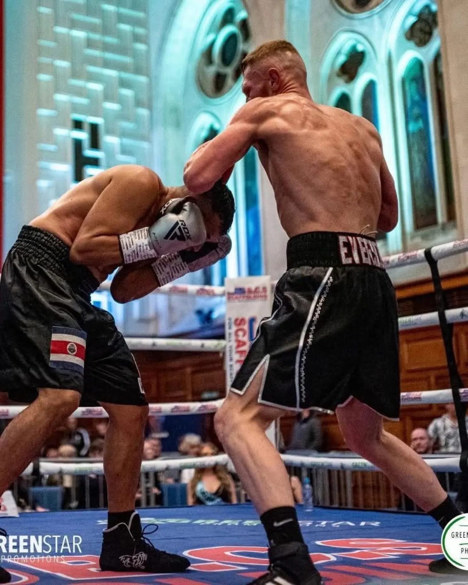Lewis Everson in EVERSON shorts pressing forward with a right hand in a church-style venue